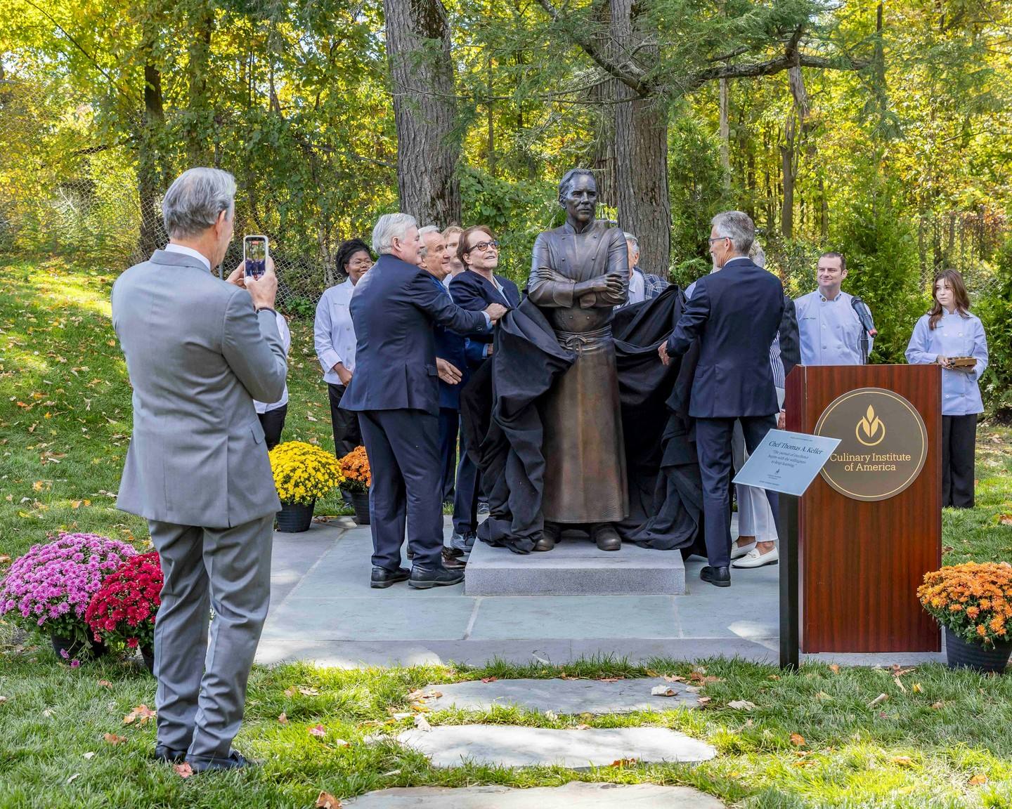 Guests pull the drape from Huether's bronze during the unveiling ceremony, as a CIA podium bearing Keller's name stands at right.