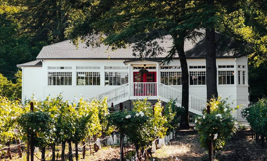 AXR Napa Valley's white farmhouse estate building with red doors, set among the vines.