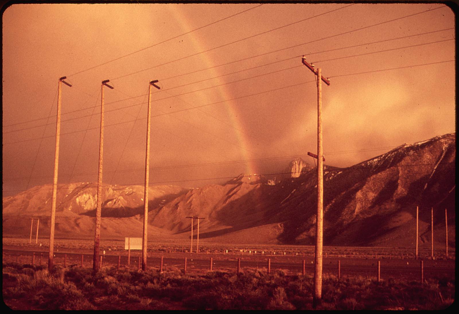 Power lines cross the country near Mono Lake beneath a rainbow, in a National Archives photograph by Dick Rowan. In the current warning, relative humidity is expected to fall into the single digits and teens in many areas.