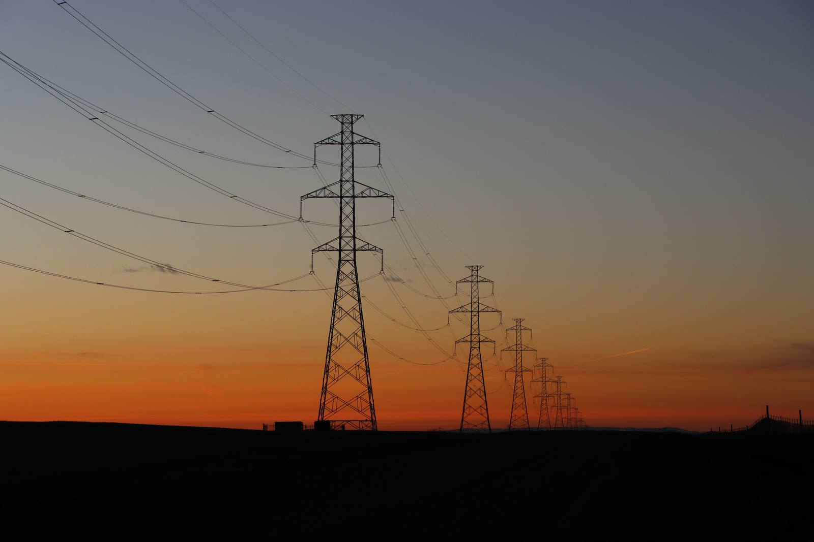 Transmission towers stand silhouetted at sunset. The red flag warning that drove the shutoffs expired Friday, and forecasters expected the marine layer to return with a cooling trend next week.