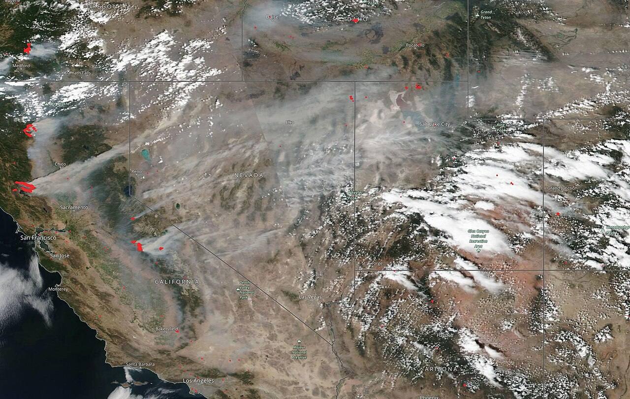 Wildfire smoke drifts across the West in this 2018 satellite image; prosecutors say the suspect admitted dumping hot ashes.