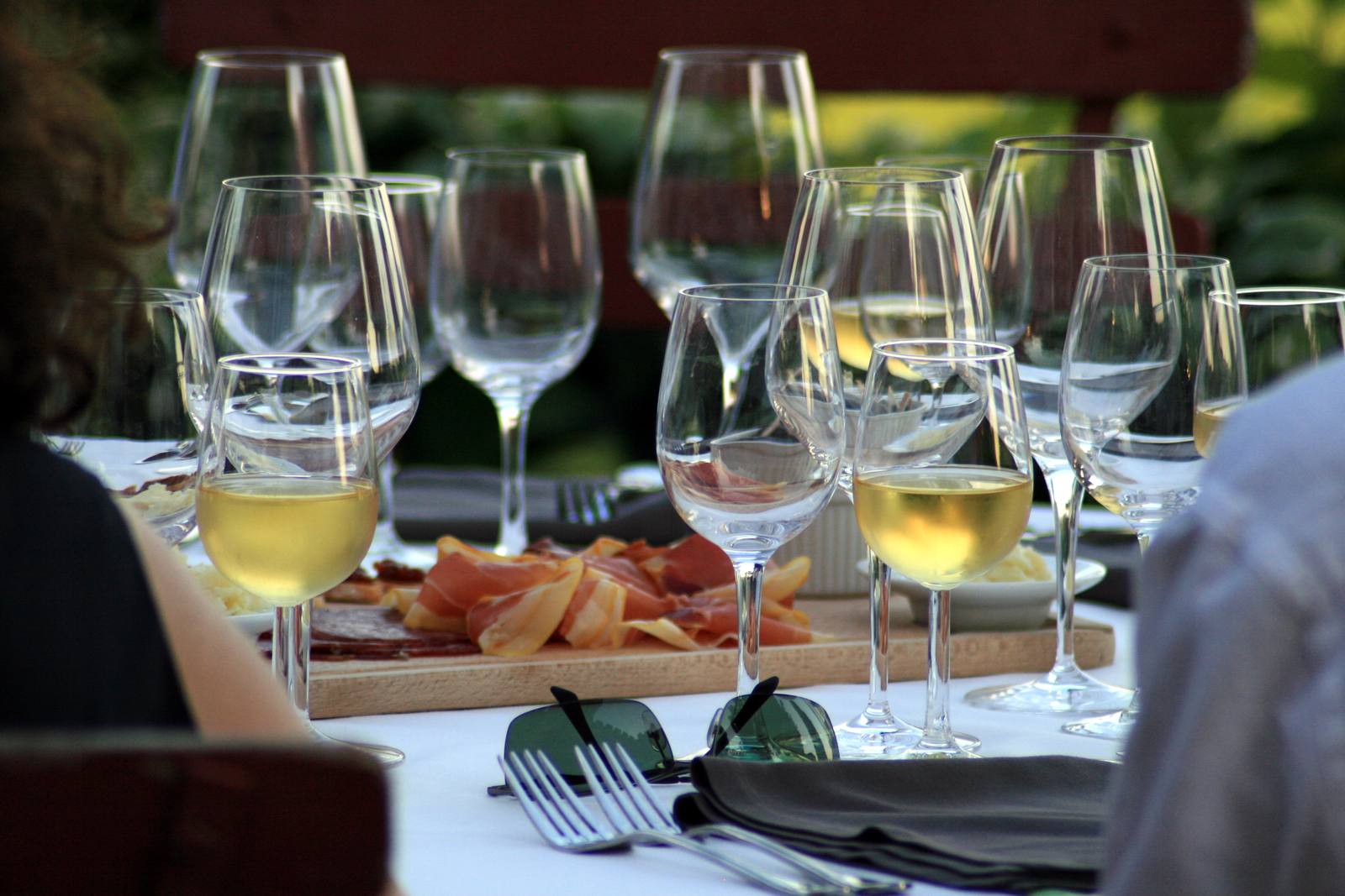 Wine glasses and a charcuterie board set for a dinner. Under SB 1273, wineries can use videos up to 60 seconds long on social media to promote winemaker dinners and tasting events at licensed retailers.